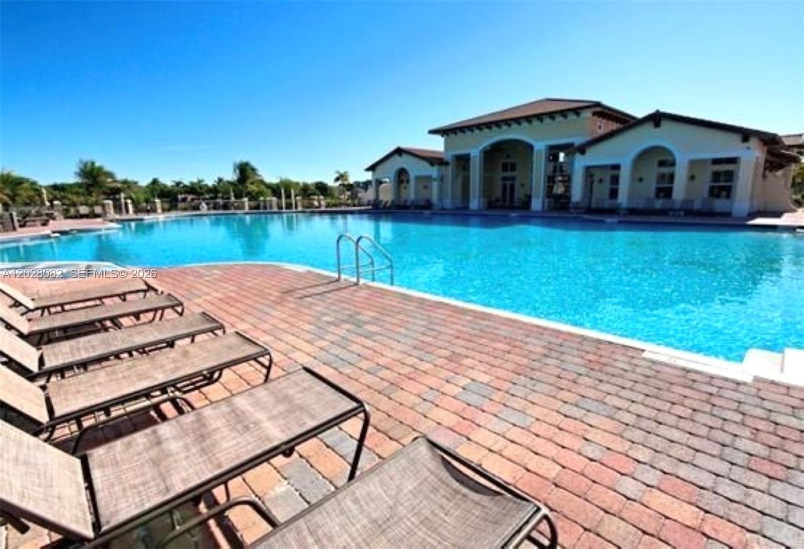 A swimming pool sits in front of a clubhouse with lounge chairs on the patio — 22541 SW 88th Pl # 6, Cutler Bay FL 33190, CUTLER BAY, FL