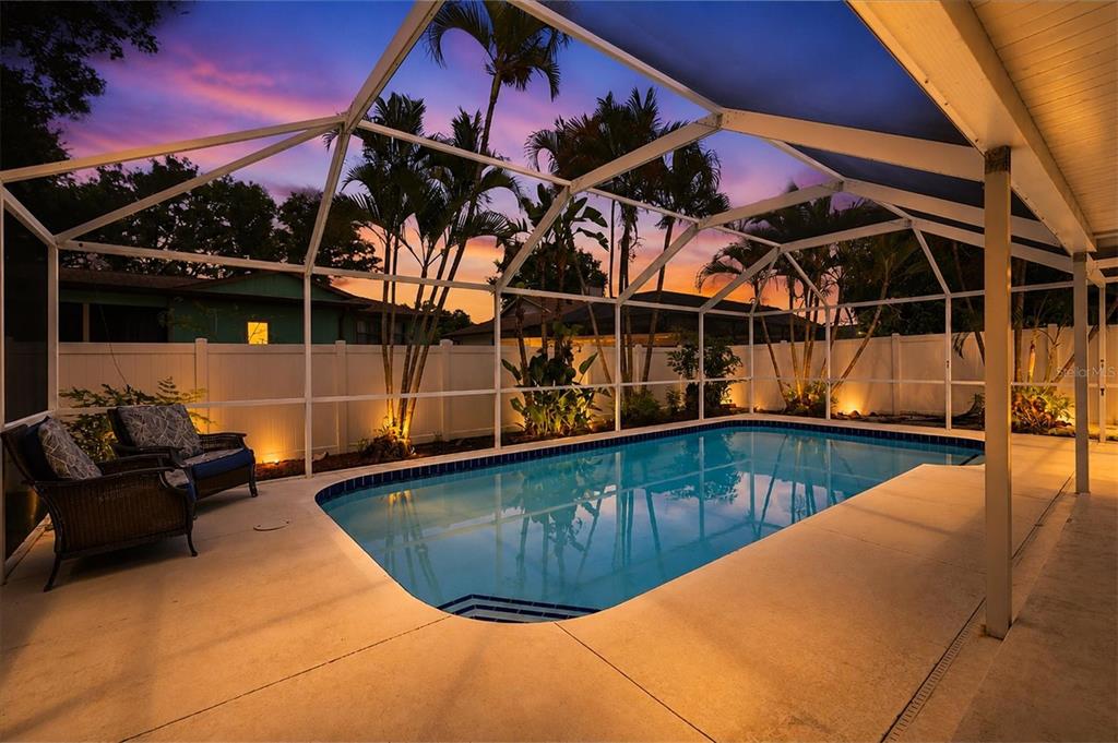 A screened-in swimming pool with a patio and palm trees at sunset — 4089 KING RICHARD DRIVE, SARASOTA, FL