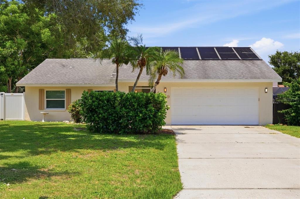 A single-story house with a white garage, solar panels on the roof, and palm trees — 4089 KING RICHARD DRIVE, SARASOTA, FL