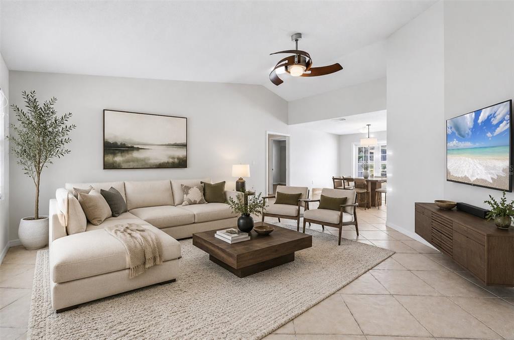 A living room features a beige sectional, wooden coffee table, two armchairs, and a ceiling fan — 4089 KING RICHARD DRIVE, SARASOTA, FL