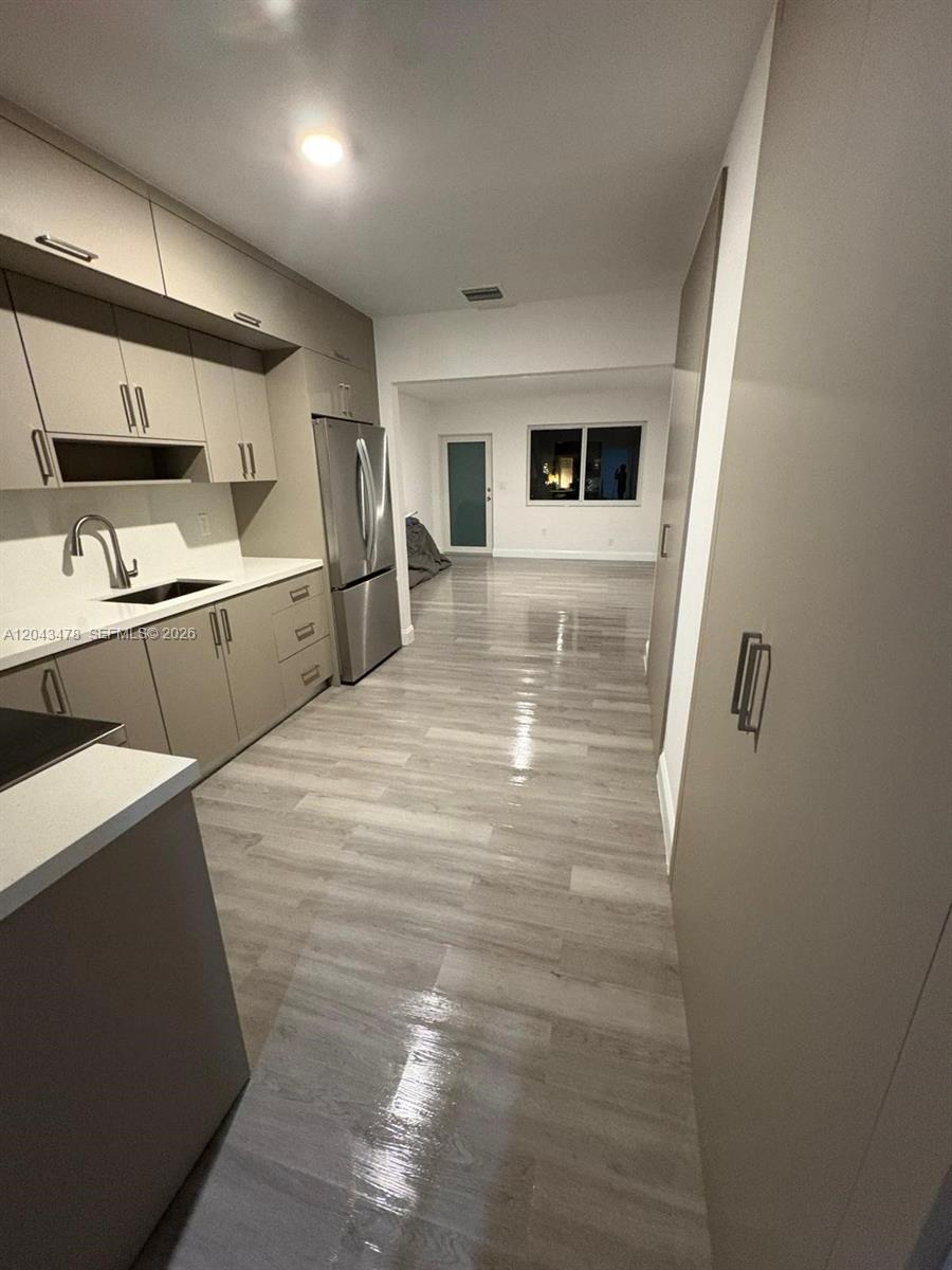 A modern kitchen features light wood-toned cabinetry, stainless steel appliances, and light-colored wood-look flooring — 225 SW 76th Ct # 227, Miami FL 33144, MIAMI, FL