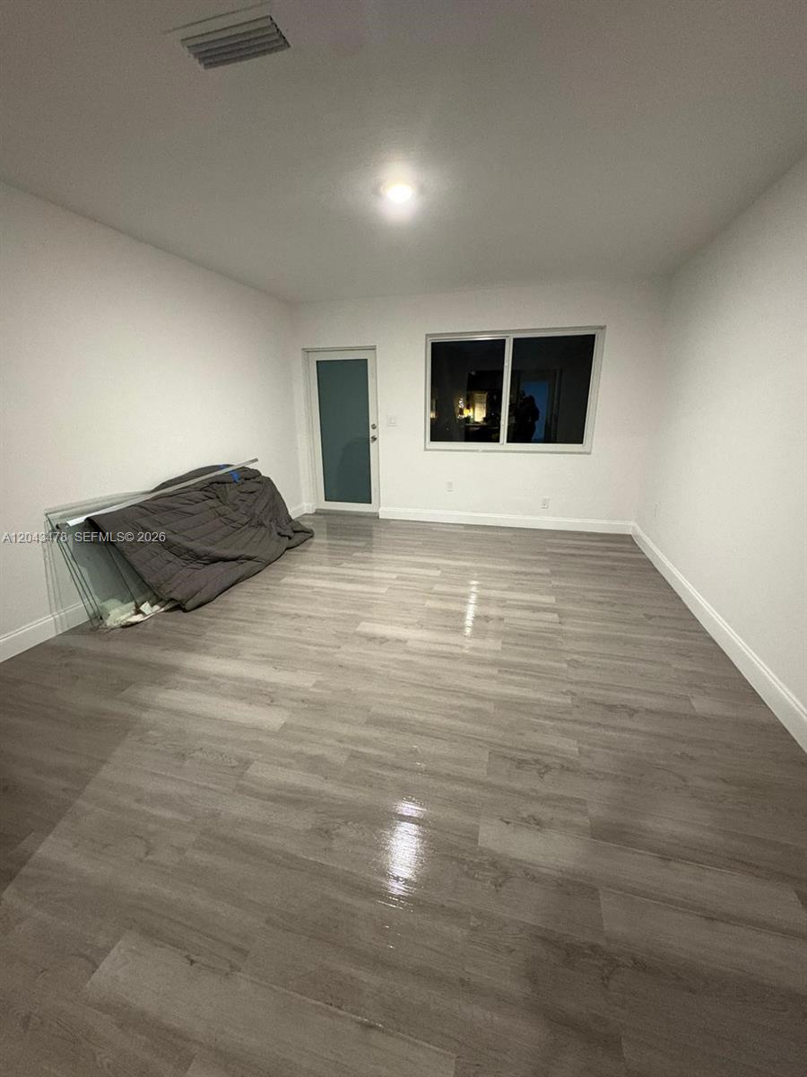 An empty room features light gray wood-look flooring, white walls, a single window, and a door — 225 SW 76th Ct # 227, Miami FL 33144, MIAMI, FL