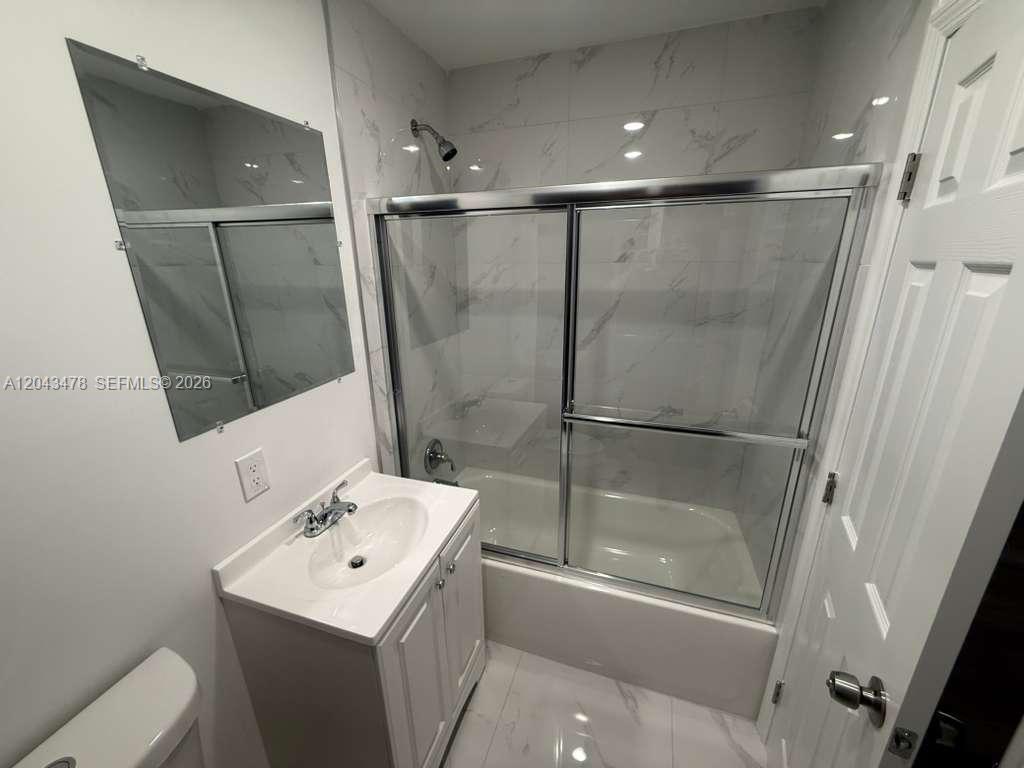 A bathroom features a white vanity, a mirror, and a shower-tub combination with marble-look tiles — 225 SW 76th Ct # 227, Miami FL 33144, MIAMI, FL