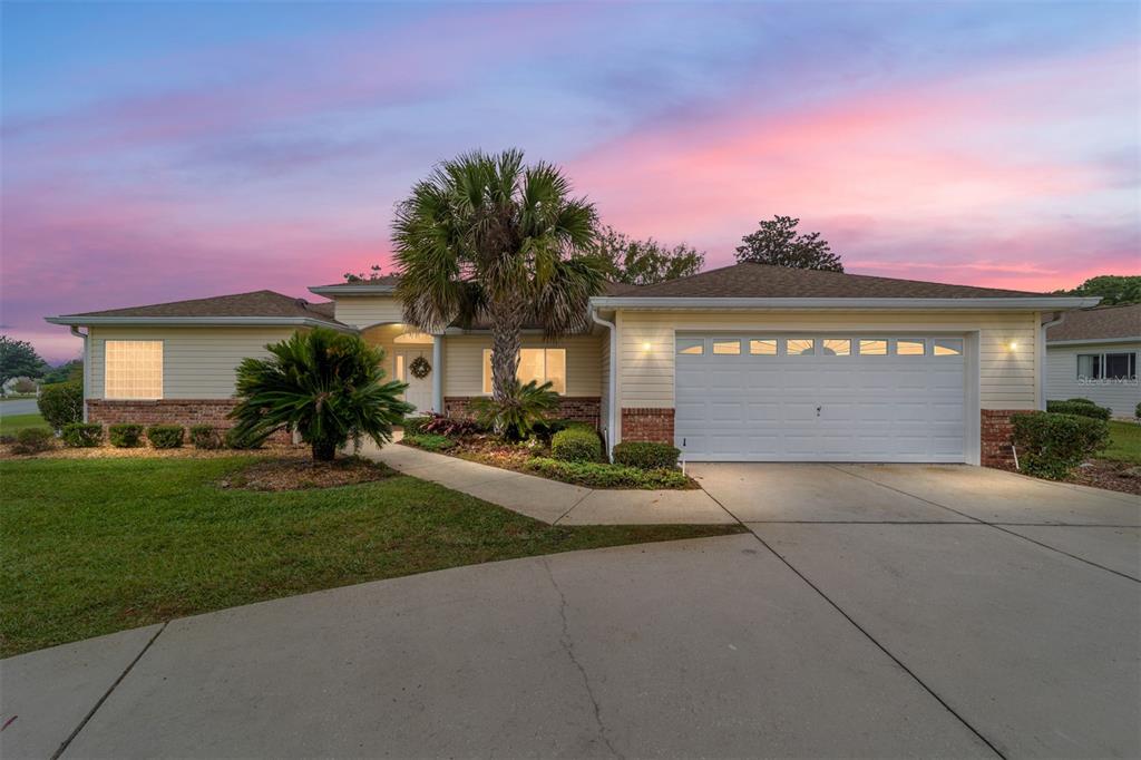 A single-story house with light yellow siding, a brick base, and a two-car garage — 13766 SE 89TH AVENUE, SUMMERFIELD, FL