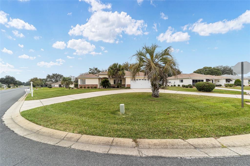 A single-story house with a beige exterior and a circular driveway sits on a corner lot — 13766 SE 89TH AVENUE, SUMMERFIELD, FL