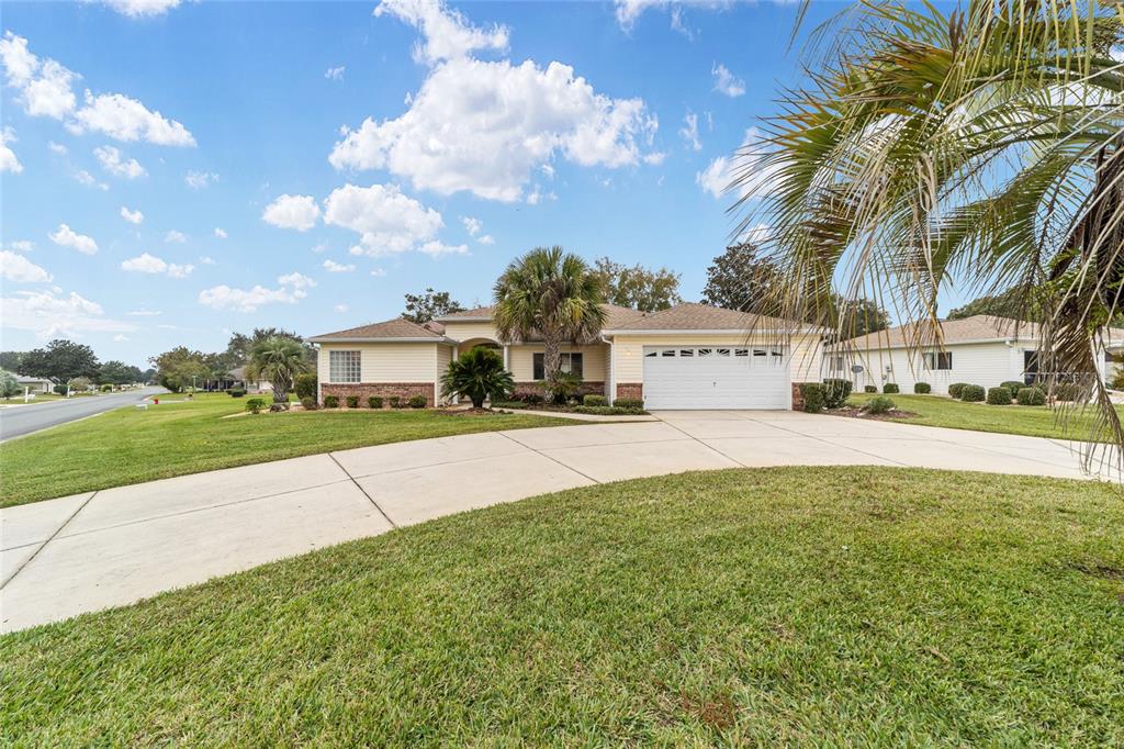 A single-story house with a two-car garage, light siding, and a large concrete driveway — 13766 SE 89TH AVENUE, SUMMERFIELD, FL