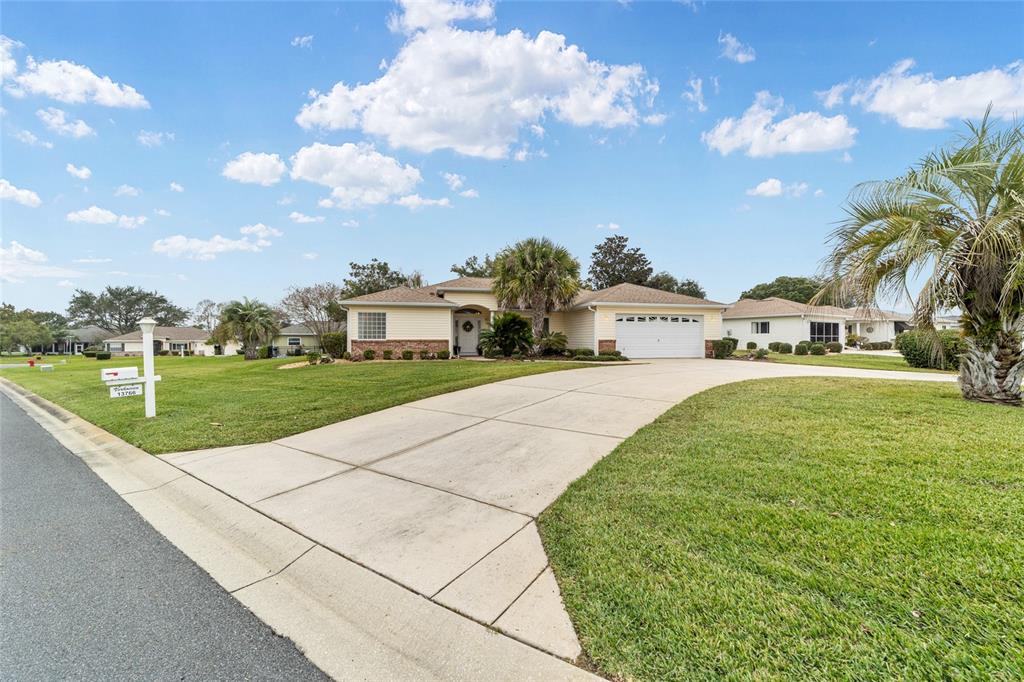A single-story house with light siding, a brick accent, and a concrete driveway — 13766 SE 89TH AVENUE, SUMMERFIELD, FL