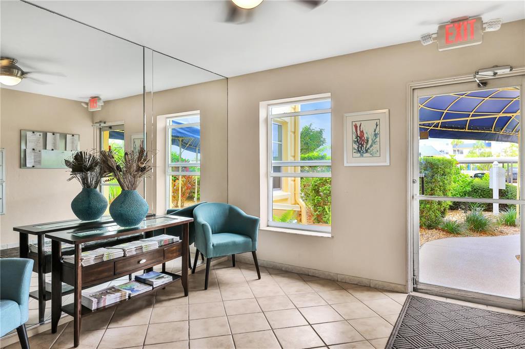 A lobby area features tile floors, a console table, teal chairs, and a glass door — 3806 GULF OF MEXICO DR DRIVE UNIT C210, LONGBOAT KEY, FL