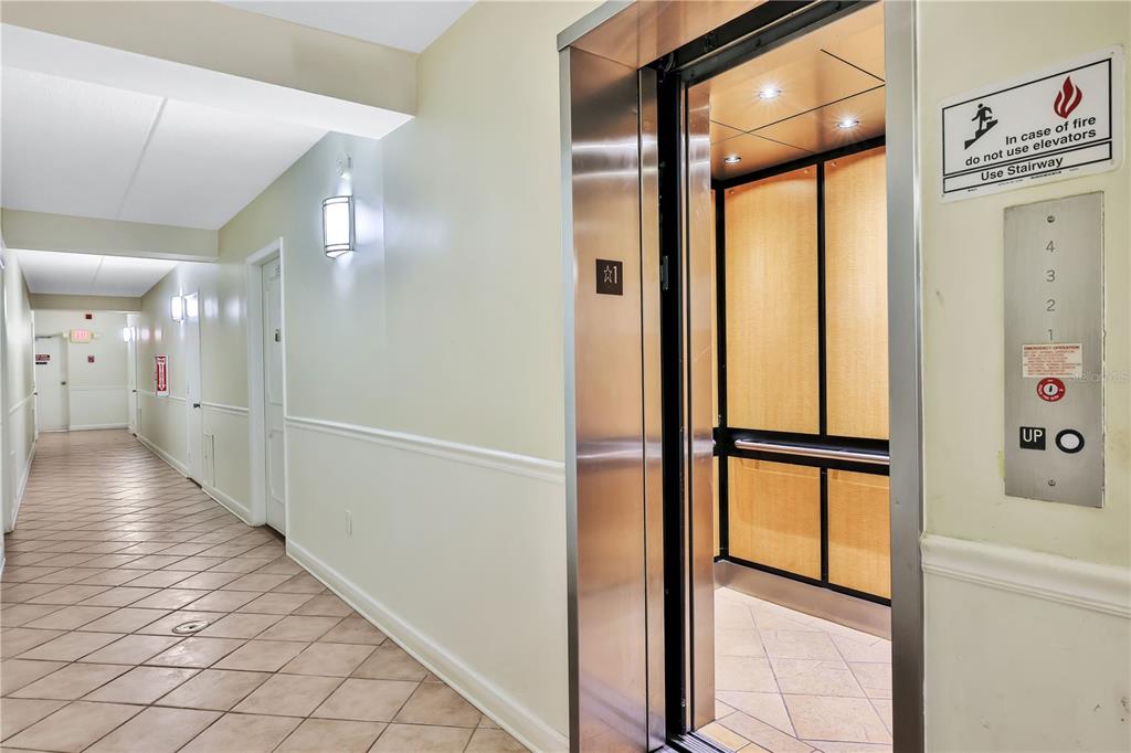 An elevator with a metal frame opens into a tiled hallway with light-colored walls — 3806 GULF OF MEXICO DR DRIVE UNIT C210, LONGBOAT KEY, FL