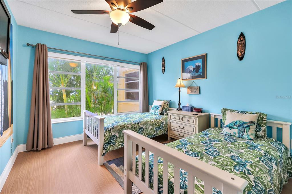 A bedroom with light blue walls, two twin beds with tropical bedding, and a ceiling fan — 3806 GULF OF MEXICO DR DRIVE UNIT C210, LONGBOAT KEY, FL