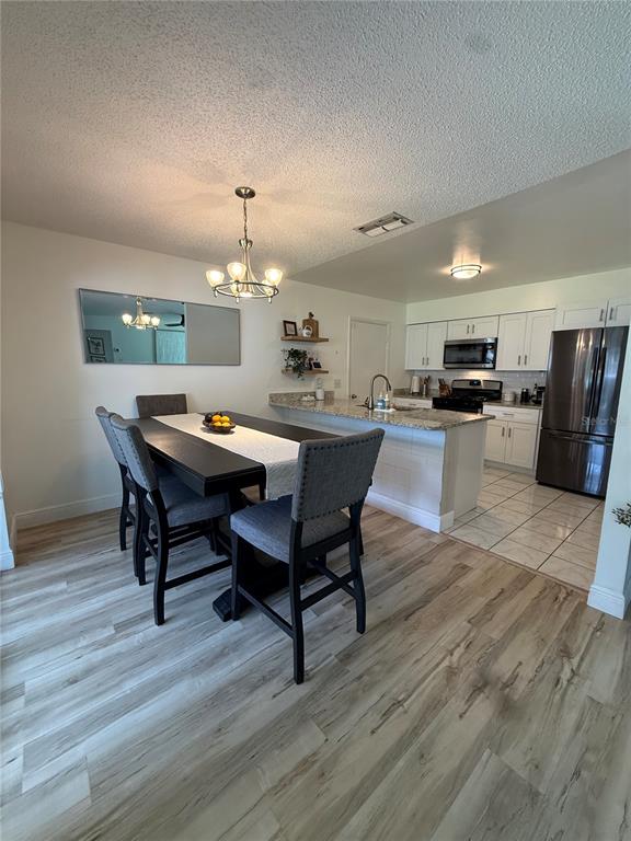 A dining area with a dark table and chairs sits adjacent to a white kitchen — 4808 GANIMEDE LANE, ORLANDO, FL