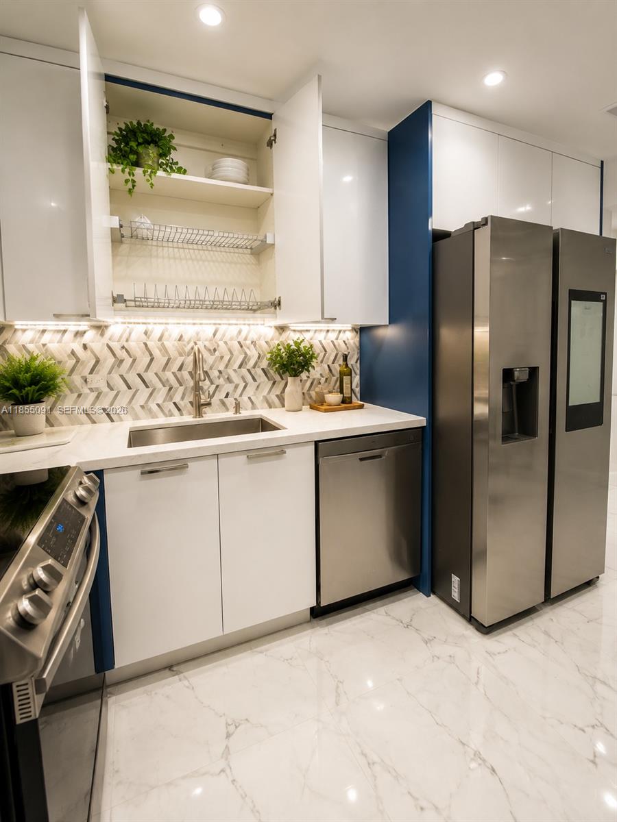 A modern kitchen features white cabinets, stainless steel appliances, and a chevron-patterned tile backsplash — 5005 Collins Ave # 822, Miami Beach FL 33140, MIAMI BEACH, FL