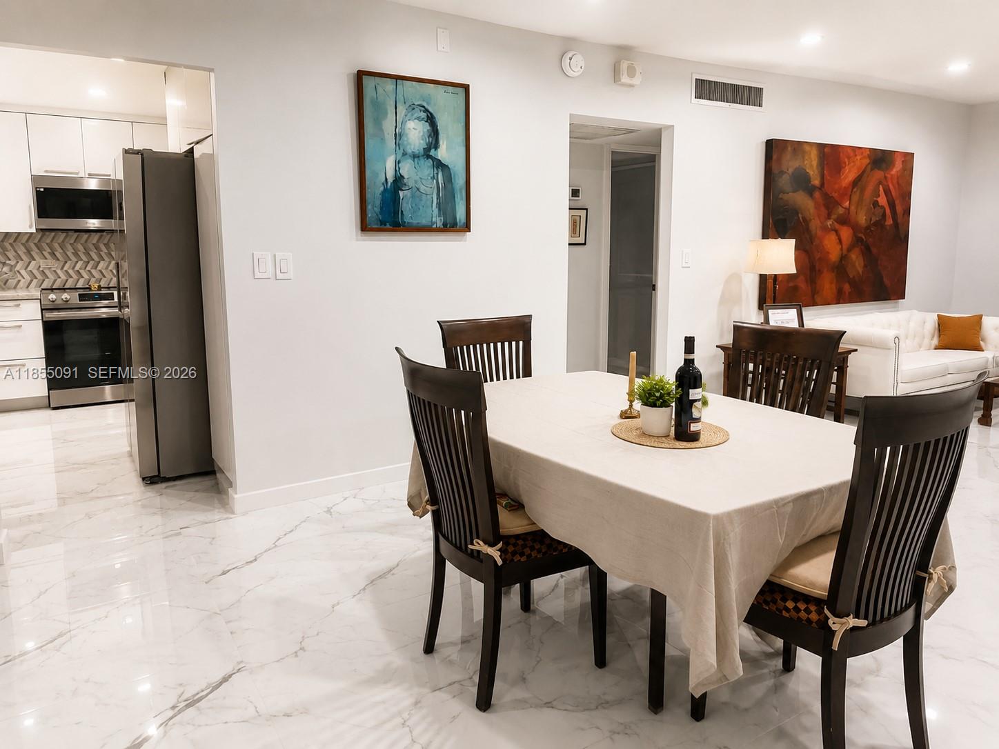 A dining area with a table and chairs sits adjacent to a modern kitchen — 5005 Collins Ave # 822, Miami Beach FL 33140, MIAMI BEACH, FL