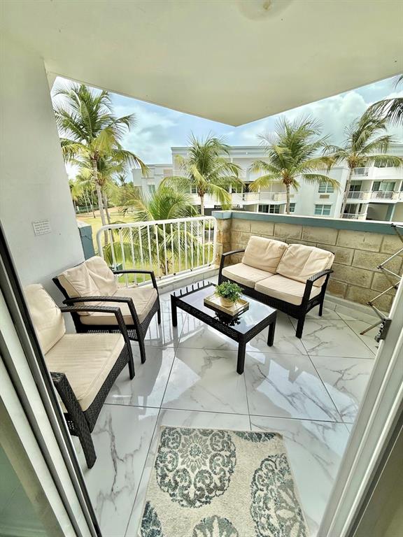 A balcony with wicker furniture, a glass-top coffee table, and white marble-look tile flooring — 968 ROAD LAS  PICUAS UNIT AB 302, RIO GRANDE, PR