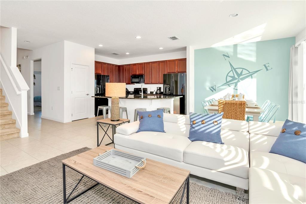 A living room with a white sectional sofa, wood coffee table, and open kitchen area — 4494 MONADO DRIVE, KISSIMMEE, FL