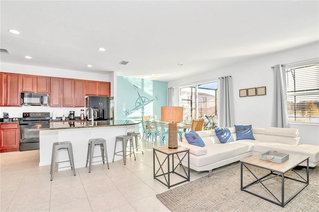 An open-concept kitchen and living area features white tile floors and a compass wall mural — 4494 MONADO DRIVE, KISSIMMEE, FL