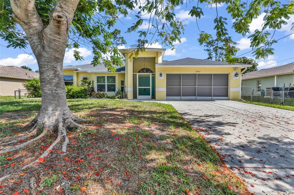 A yellow single-story house with a large tree in the front yard and a driveway — 3660 MADAGASCAR AVENUE, NORTH PORT, FL