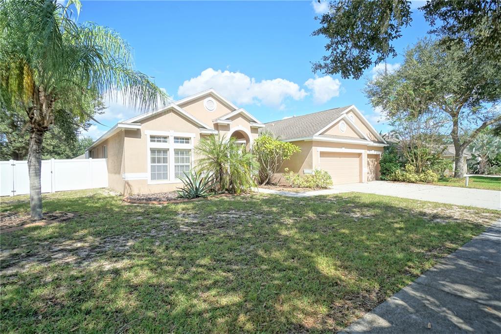 A tan single-story house with a two-car garage and a palm tree in the yard — 12402 WINDMILL COVE DRIVE, RIVERVIEW, FL