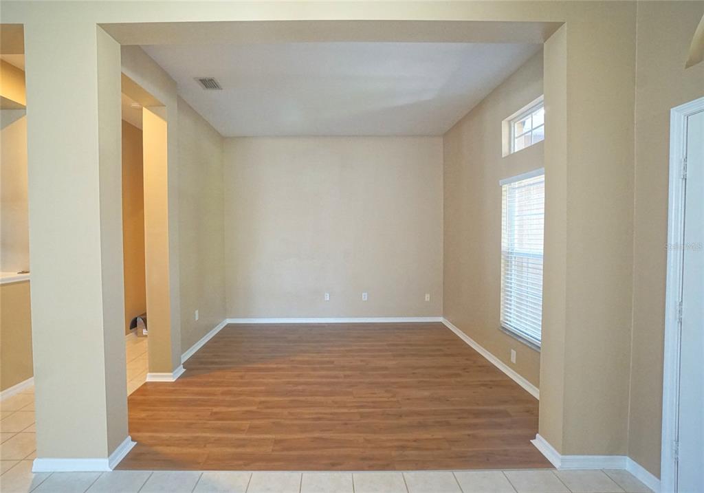 An empty room with light-colored walls, wood-look flooring, and a window with blinds — 12402 WINDMILL COVE DRIVE, RIVERVIEW, FL