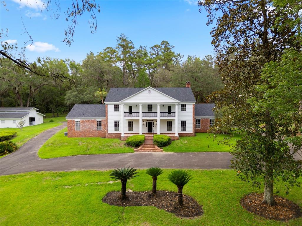 A two-story brick house with a white columned portico sits on a grassy lot — 7216 NW 20TH PLACE, GAINESVILLE, FL