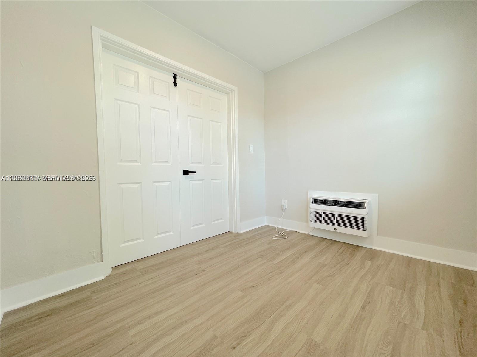 This room features light-colored wood-look flooring, white double closet doors, and a wall-mounted air conditioner — 1836 Dewey St # 2, Hollywood FL 33020, HOLLYWOOD, FL
