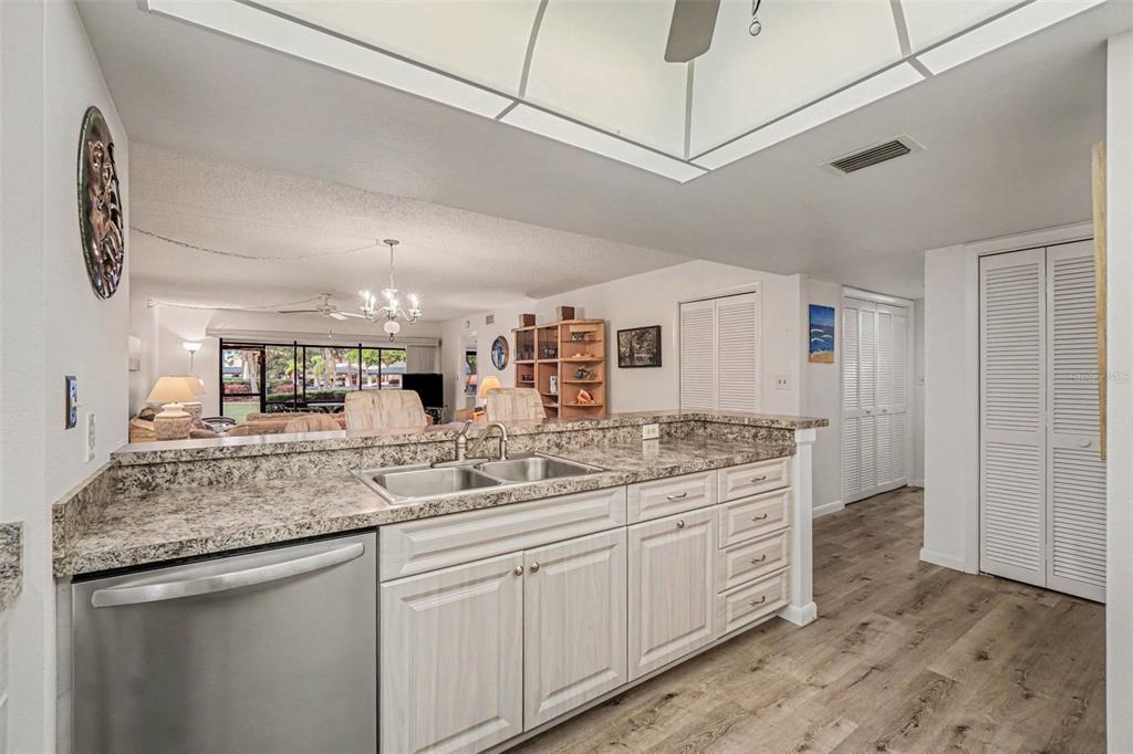 A kitchen with granite countertops, light wood cabinets, and stainless steel appliances overlooks a living area — 601 SHREVE STREET UNIT 66A, PUNTA GORDA, FL