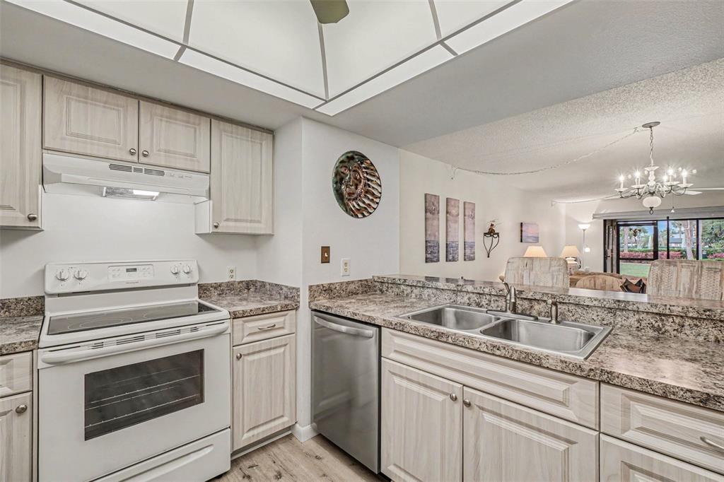 A kitchen with light wood cabinets, granite countertops, white appliances, and a stainless steel dishwasher — 601 SHREVE STREET UNIT 66A, PUNTA GORDA, FL
