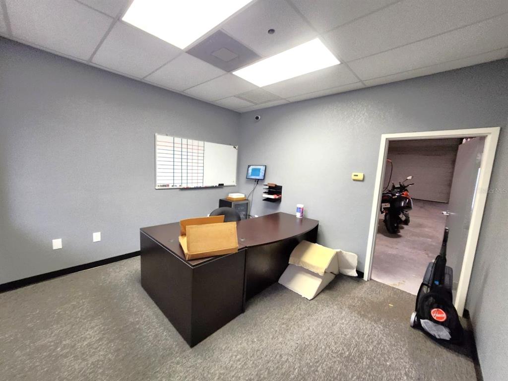 An office with gray walls, a dark desk, a whiteboard, and a doorway to a garage — 2135 S 30TH STREET, HAINES CITY, FL