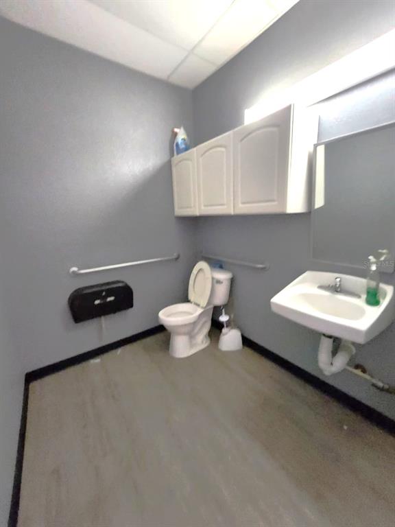A commercial restroom features gray walls, white cabinets, a toilet, and a wall-mounted sink — 2135 S 30TH STREET, HAINES CITY, FL