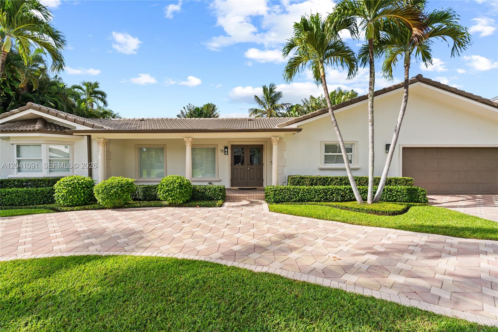 A single-story house with a paved driveway, manicured hedges, and palm trees in the front — 18 Eleuthera Dr, Ocean Ridge FL 33435, OCEAN RIDGE, FL