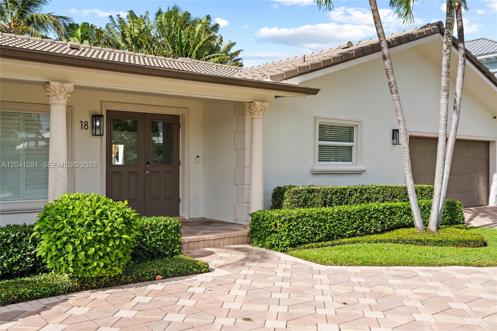 A paved walkway leads to the front entrance of a house with a brown door — 18 Eleuthera Dr, Ocean Ridge FL 33435, OCEAN RIDGE, FL
