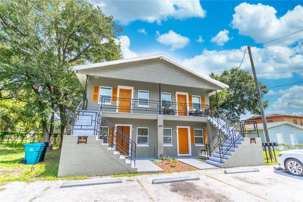 A two-story apartment building with exterior staircases, orange doors, and a parking lot in front — 1207 W CYPRESS STREET, ORLANDO, FL