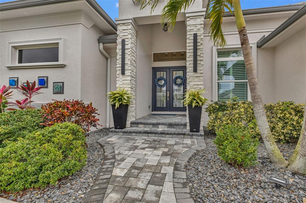 A stone-paved walkway leads to the double front doors of a house with stone columns — 125 GREAT ISAAC COURT, PUNTA GORDA, FL