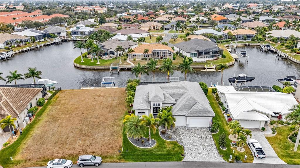 An aerial view shows a vacant lot next to a house with a paved driveway — 125 GREAT ISAAC COURT, PUNTA GORDA, FL