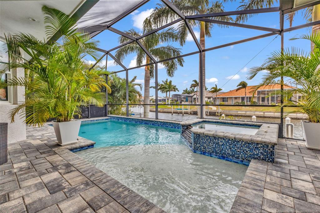 A screened-in pool and spa area with paver decking overlooking a canal — 125 GREAT ISAAC COURT, PUNTA GORDA, FL