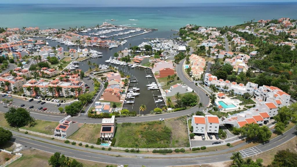 An aerial view shows a coastal residential community with a marina, swimming pools, and roads — HARBOUR DRIVE DR. #13 E PALMAS DEL MAR, HUMACAO, PR
