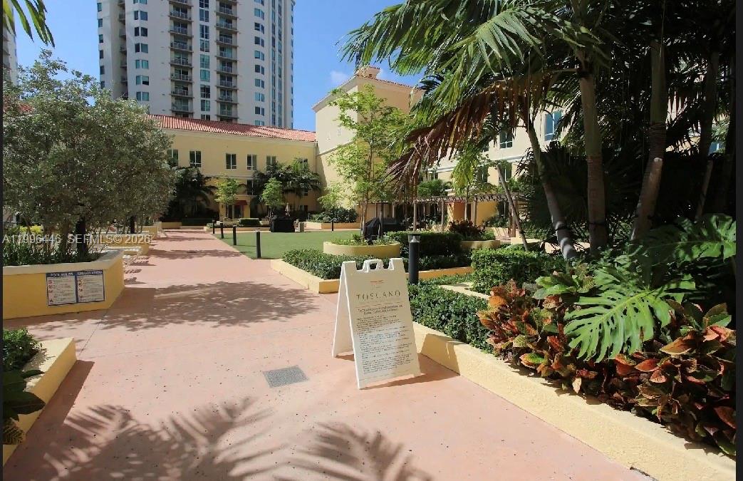 An outdoor courtyard features a paved walkway, manicured landscaping, palm trees, and a residential building — 7350 SW 89th St # 1102S, Miami FL 33156, MIAMI, FL