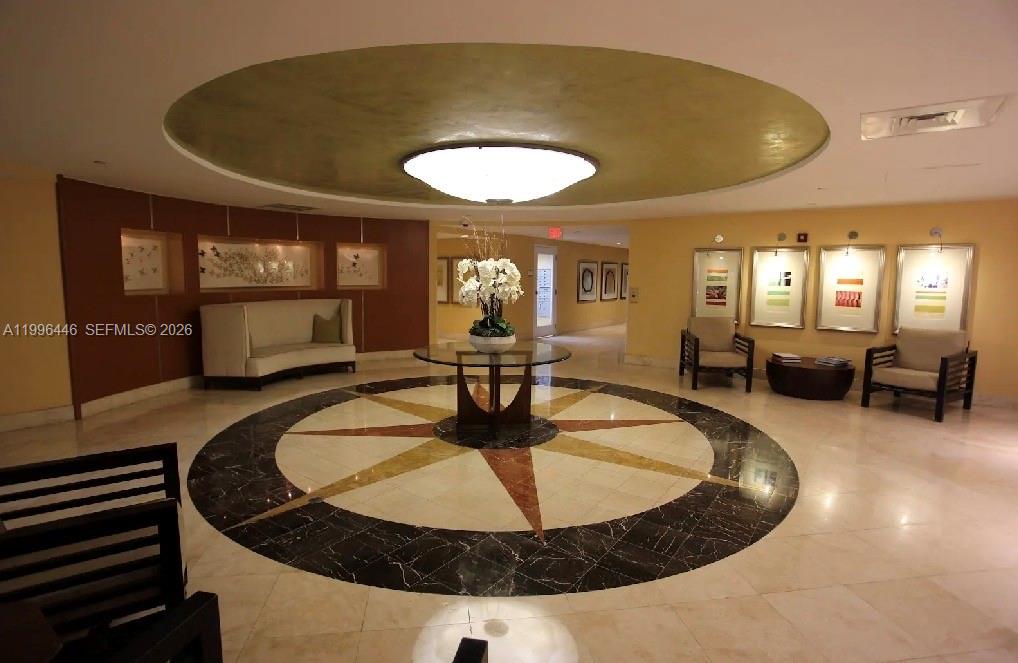 A lobby features a circular floor inlay, a central table with flowers, and seating areas — 7350 SW 89th St # 1102S, Miami FL 33156, MIAMI, FL