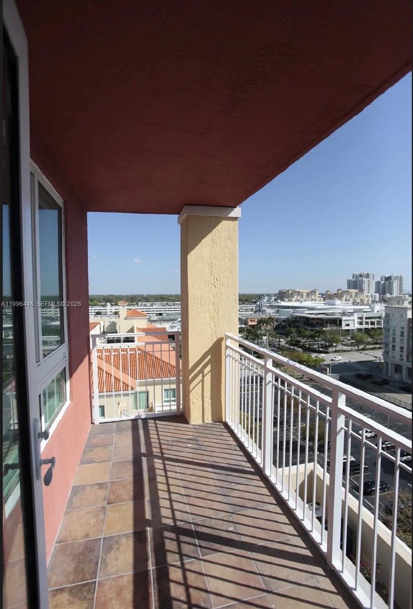 A balcony with tiled flooring and white railings overlooks a city street and buildings — 7350 SW 89th St # 1102S, Miami FL 33156, MIAMI, FL