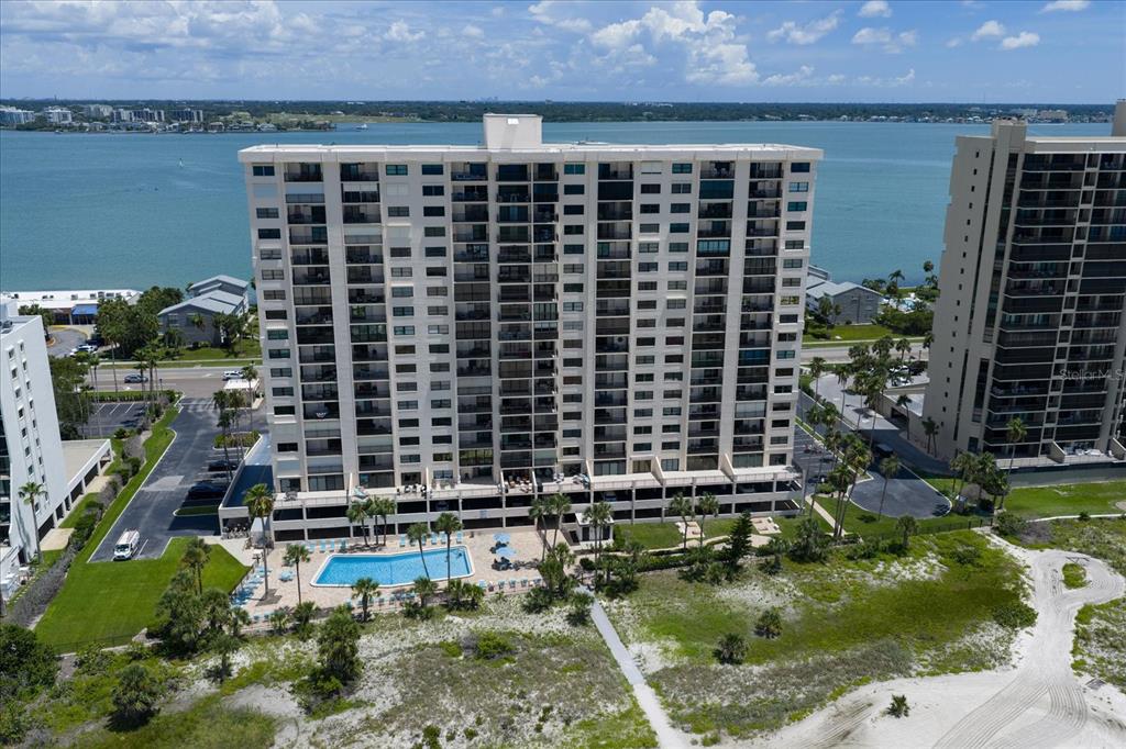 An aerial view of a tall residential building with a swimming pool and beach access — 1270 GULF BOULEVARD UNIT 1503, CLEARWATER BEACH, FL