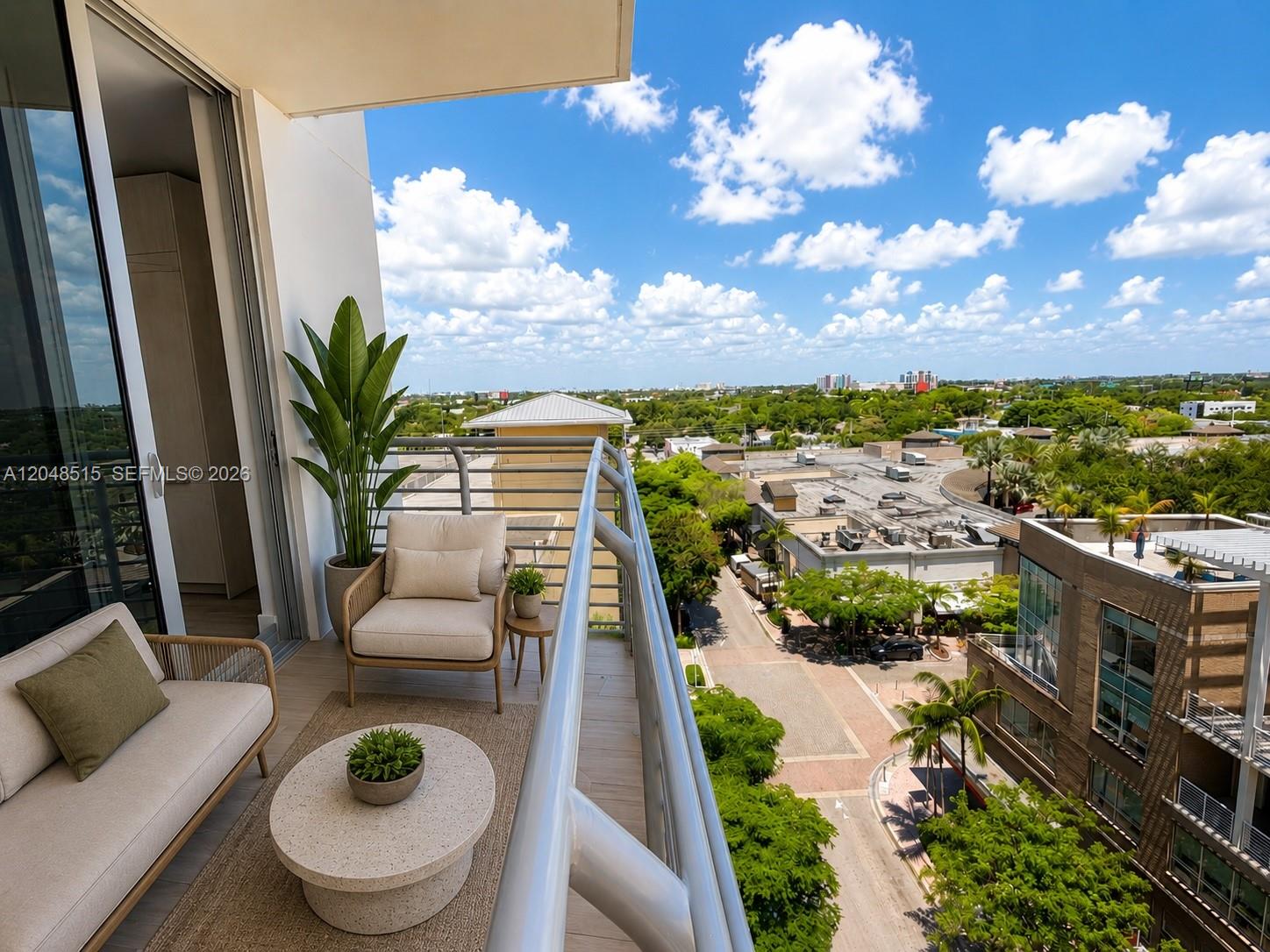 A balcony with outdoor furniture overlooks a street, surrounding buildings, and a blue sky — 90 NE 32nd St # 814, Miami FL 33137, MIAMI, FL