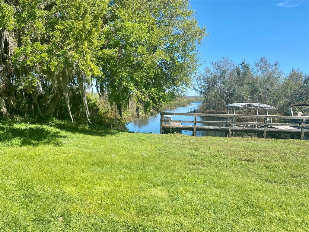 A grassy lawn leads to a wooden dock on a canal surrounded by trees — 1051 GREEN GATE BOULEVARD, GROVELAND, FL