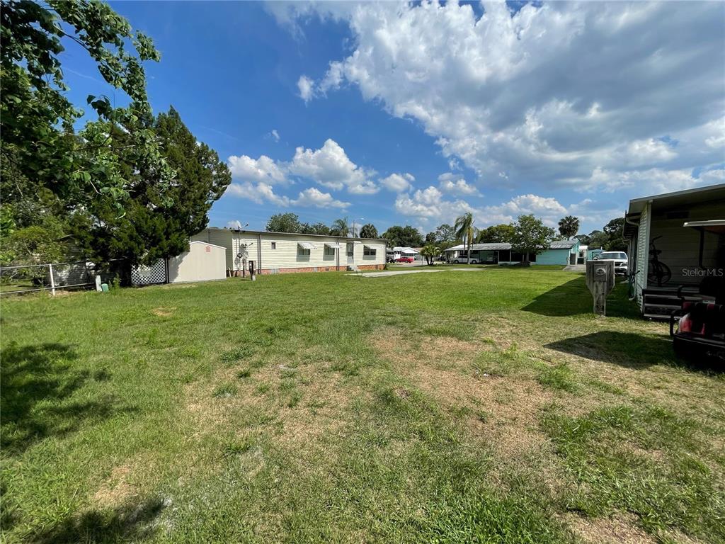 A grassy backyard area with a mobile home and a shed under a cloudy sky — 162 LEISURE WORLD DRIVE N, DEBARY, FL