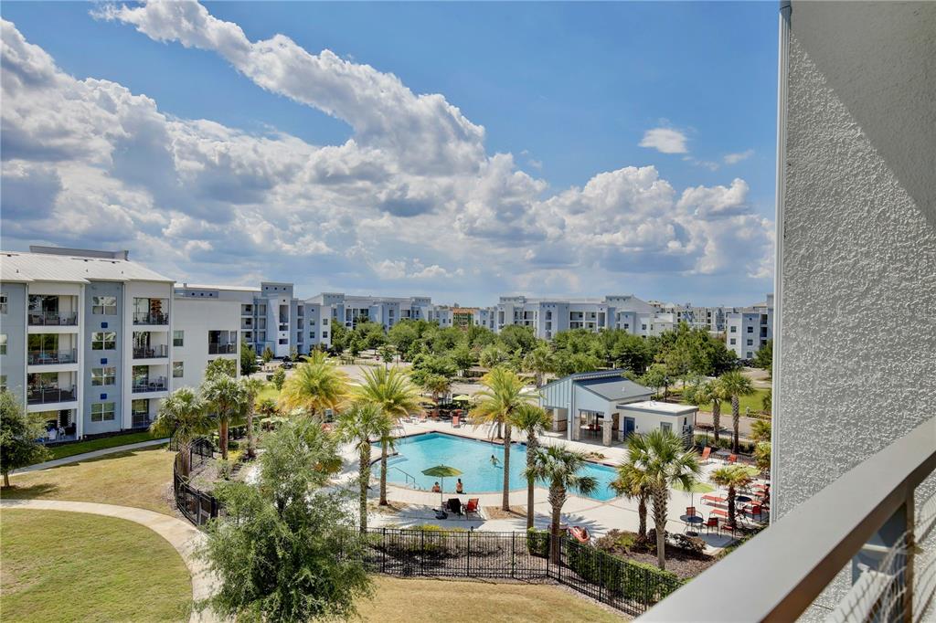 An elevated view of an apartment complex pool area with palm trees and surrounding buildings — 3180 PARADOX CIRCLE UNIT 402, KISSIMMEE, FL