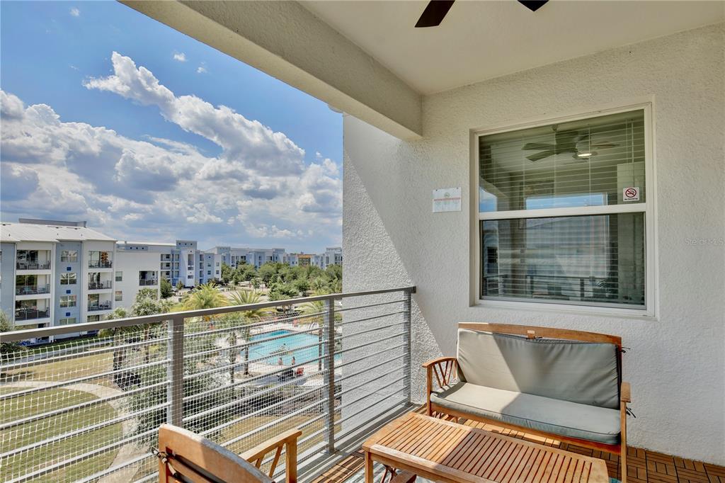 A balcony with a metal railing overlooks a swimming pool and apartment buildings — 3180 PARADOX CIRCLE UNIT 402, KISSIMMEE, FL
