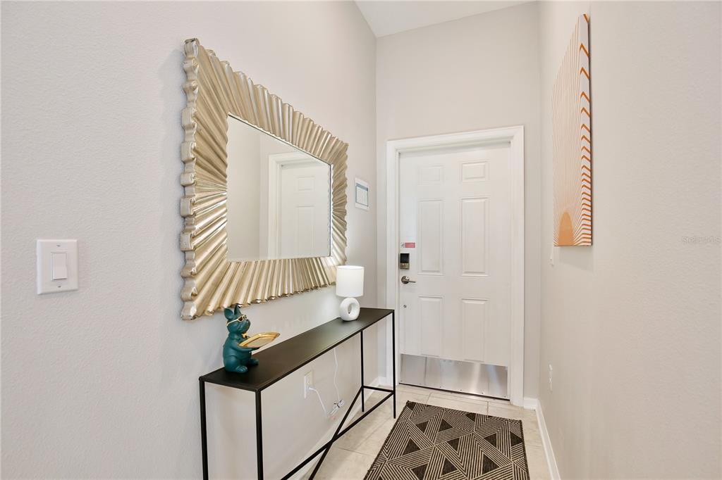 An entryway features a console table, a large decorative mirror, and a white front door — 3180 PARADOX CIRCLE UNIT 402, KISSIMMEE, FL