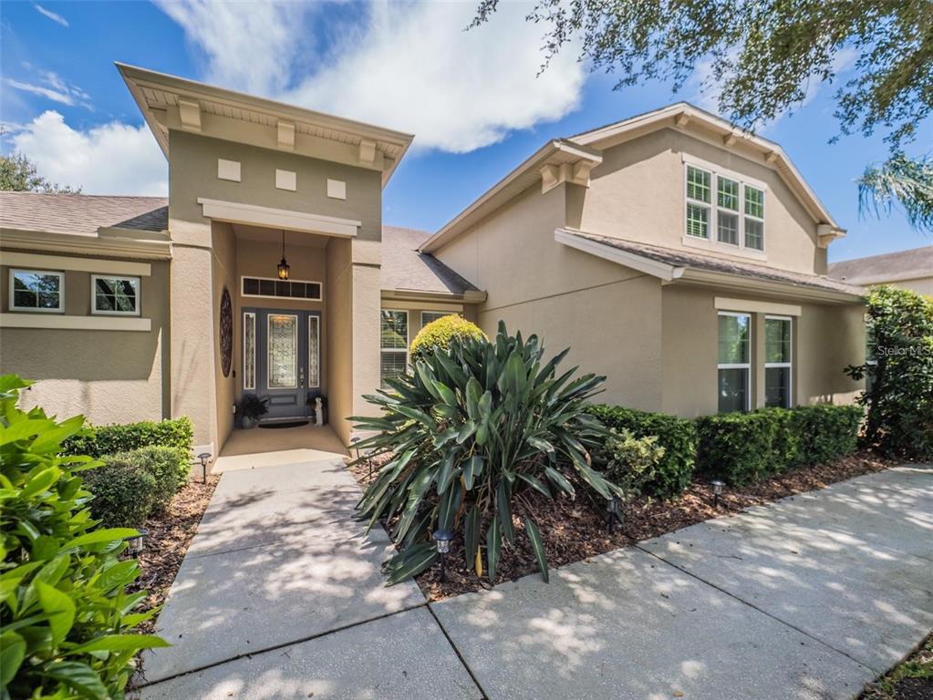 A tan two-story house with a covered entryway, a concrete walkway, and landscaped front yard — 4443 PINE GOLD AVENUE, APOPKA, FL