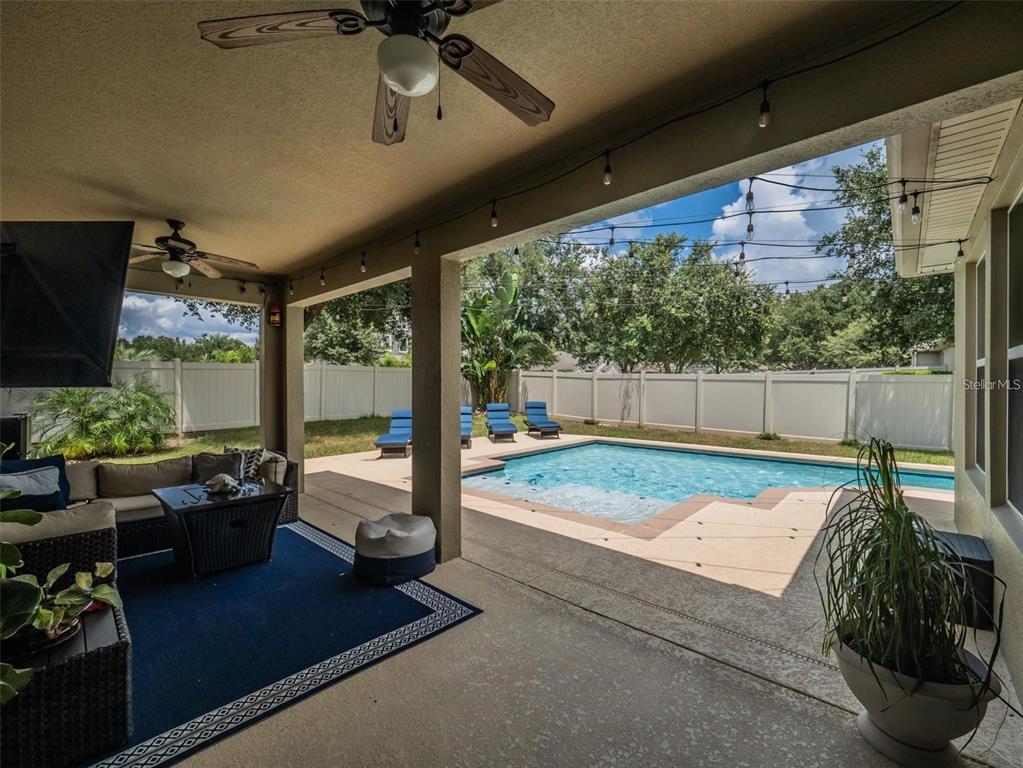 A covered patio with outdoor furniture overlooks a swimming pool and a fenced backyard — 4443 PINE GOLD AVENUE, APOPKA, FL