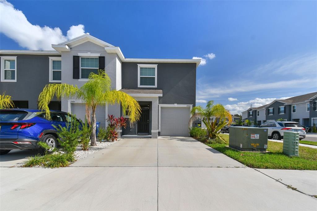 A two-story townhouse with a gray exterior, two garages, and a concrete driveway — 2880 EVERGREEN ELM PASS, WESLEY CHAPEL, FL
