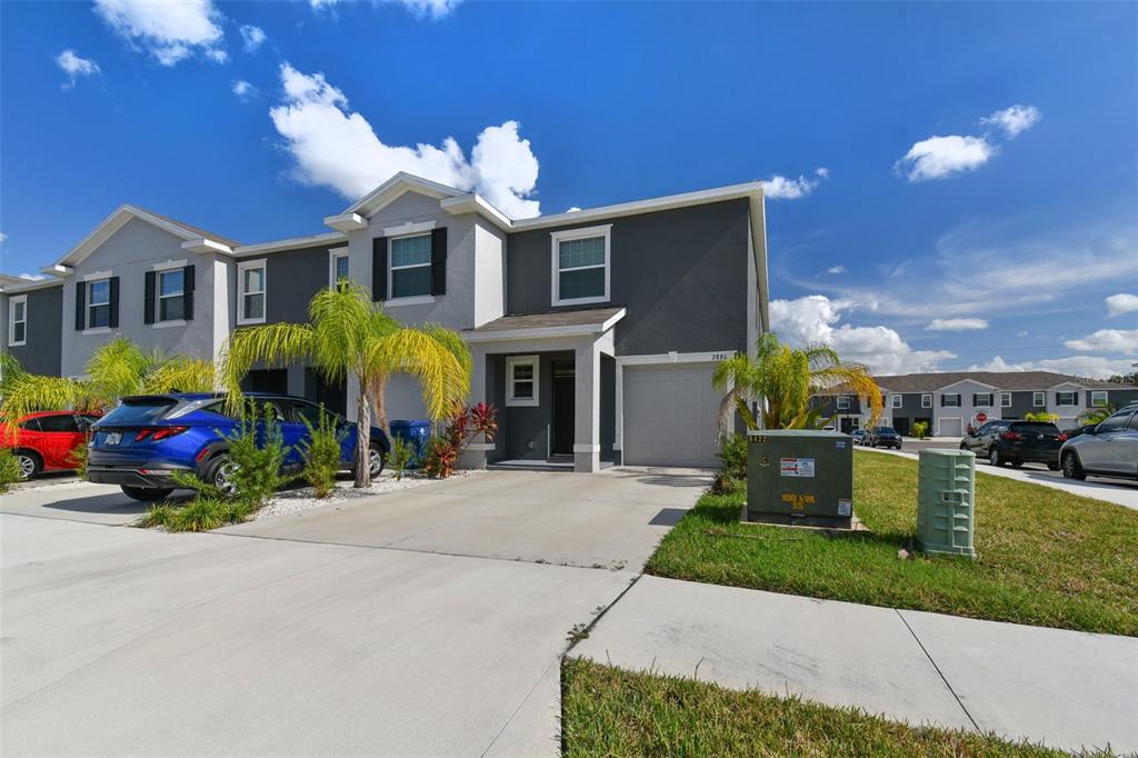 A two-story townhouse with a gray exterior, a single-car garage, and a concrete driveway — 2880 EVERGREEN ELM PASS, WESLEY CHAPEL, FL
